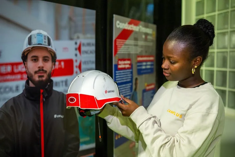 Une jeune visiteuse essaie un casque de chantier Eiffage au Parcours Imagine.